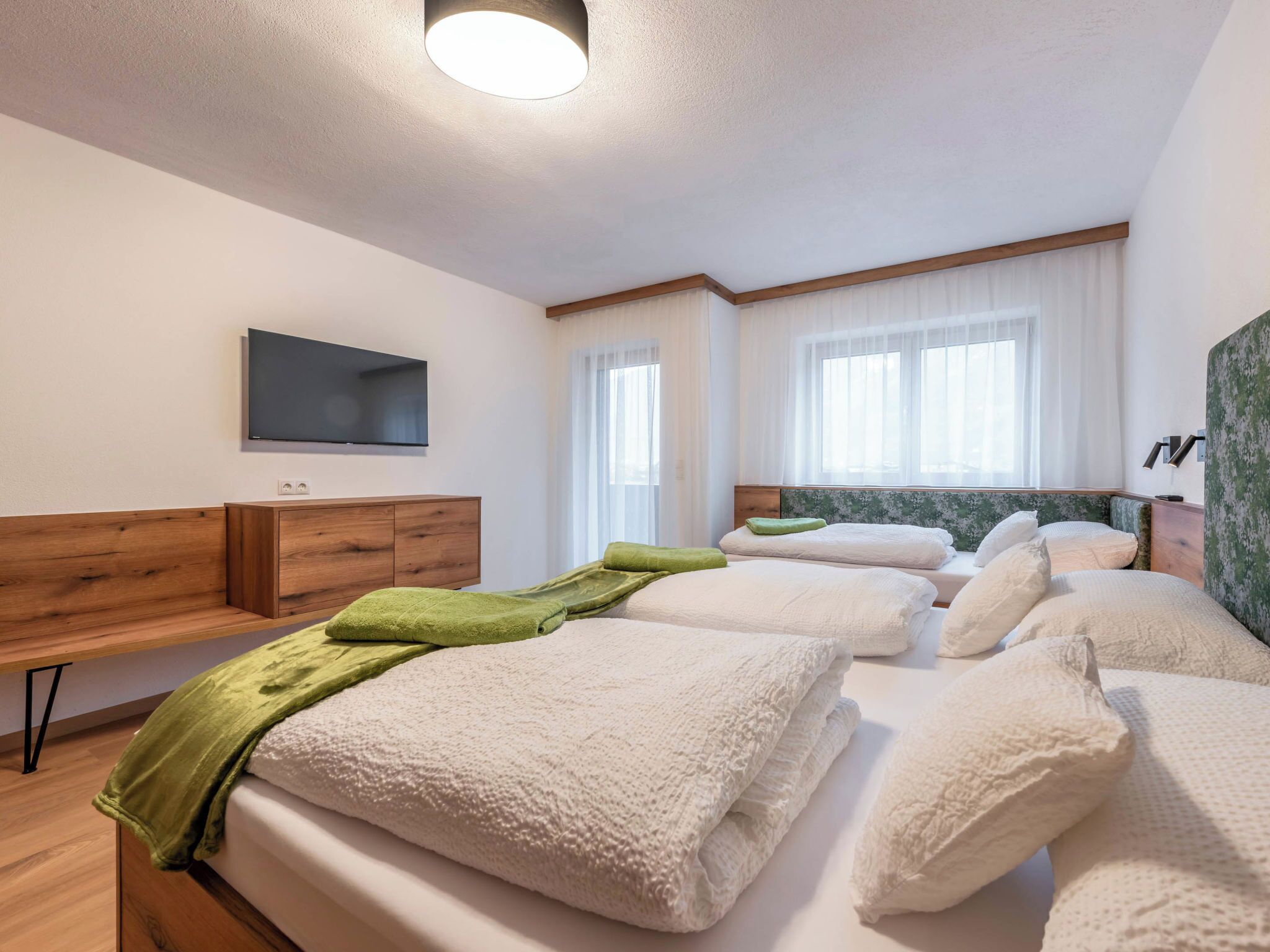 Una habitació d'hotel amb un llit, una televisió, un escriptori i una finestra.