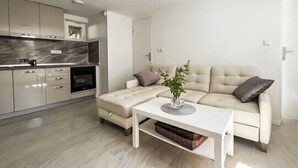 Eine moderne Küche mit integrierten Geräten, ein heller Essbereich mit Sofa und Couchtisch, und ein minimalistisches Design.
