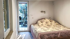 Ein Schlafzimmer mit einem Bett, einer Tür, die auf einen Balkon führt, und einem kleinen Tisch.