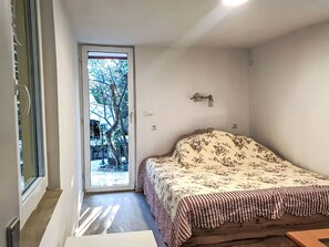 A bedroom with a bed, a door leading to a balcony, and a small table. - Beach house Suzi by Interhome (Posedarje)
