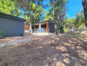Moderni ulkotila, jossa on katettu oleskelualue, kaltevakattoinen rakennus ja soralla päällystetty polku.