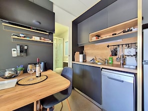 A compact kitchen with a wooden dining table, a dishwasher, and a coffee machine. - Vacation home MA-LA by Interhome (Pakoštane)