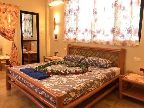 A bedroom with a bed, a nightstand, a chair, and a window with curtains.