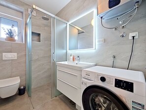 A modern bathroom with a glass shower enclosure, a built-in washing machine, and a large mirror. - Sunny Terrace by Interhome (Trogir/Okrug Gornji)