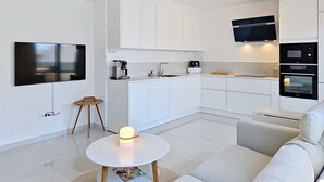 Eine moderne Küche mit weißen Schränken, einer Kaffeemaschine, einer Mikrowelle und einem Backofen.