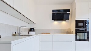 Eine moderne Küche mit weißen Schränken, einer eingebauten Mikrowelle und einem Edelstahlbackofen.
