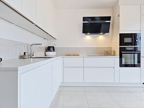 A modern kitchen with white cabinetry, a built-in microwave, and a stainless steel oven. - Sunny Terrace by Interhome (Trogir/Okrug Gornji)