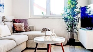 A living room with a sofa, a round coffee table with a vase, a potted plant, and a television. - Sunny Terrace II by Interhome (Trogir/Okrug Gornji)