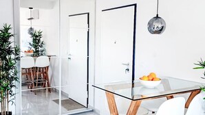 A modern dining area with a glass table, white chairs, and a bowl of fruit. - Sunny Terrace II by Interhome (Trogir/Okrug Gornji)