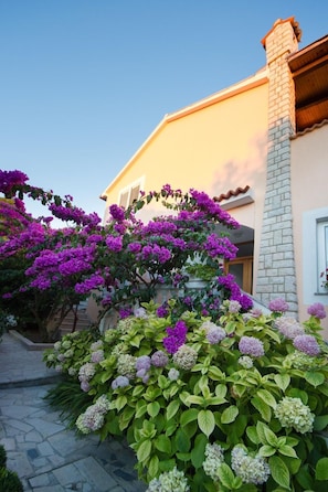A house with a stone chimney, a stone pathway, and flowering plants. - mit Terrasse by Interhome (Rab/Supetarska Draga)