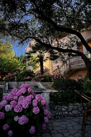 A stone pathway leading to a building with a stone wall and pink flowers. - mit Terrasse by Interhome (Rab/Supetarska Draga)