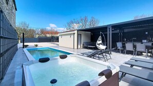 Een zwembad met ligbedden en een jacuzzi.