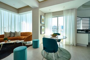 Ein modernes Wohnzimmer mit einer Couch, Hocker und einem Essbereich mit Tisch und Stühlen.