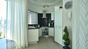 A modern kitchen with a black backsplash, white cabinets, a clock, and a potted plant. - Artdeco Exclusive Downtownsd Gym Piantini (Santo Domingo)