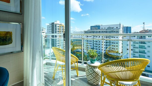 A balcony with yellow wicker chairs, a potted plant, and a patterned table. - Artdeco Exclusive Downtownsd Gym Piantini (Santo Domingo)