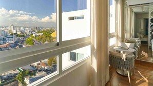 Eine moderne Wohnung mit großen Fenstern, einem Balkon und Blick auf eine Skyline.