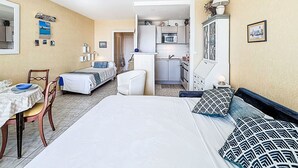 Een compacte kamer met een bed, een klein eettafeltje, een stoel, een kitchenette en een badkamer.