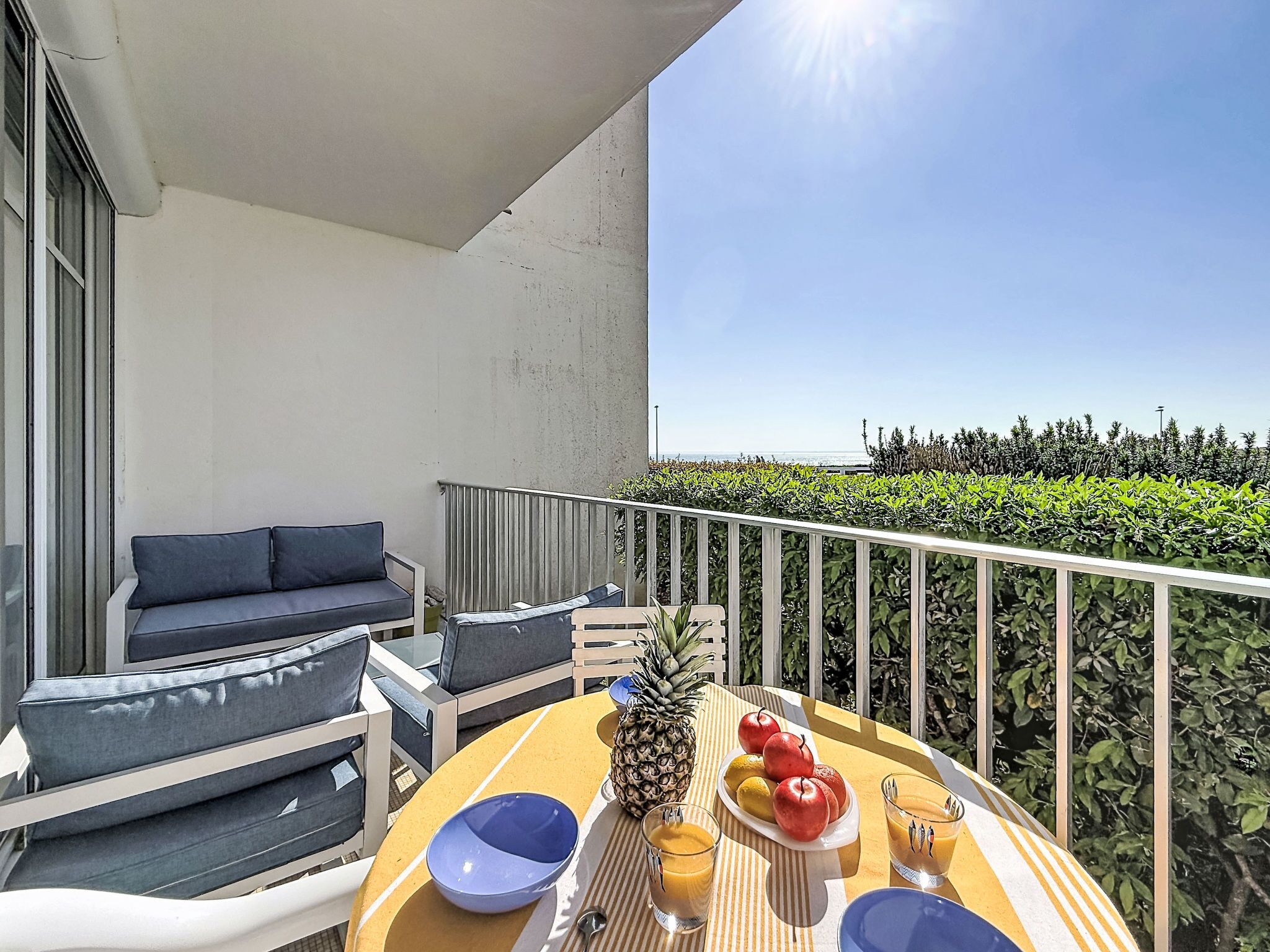 A balcony with a sofa, dining table, and a view of the sea.
