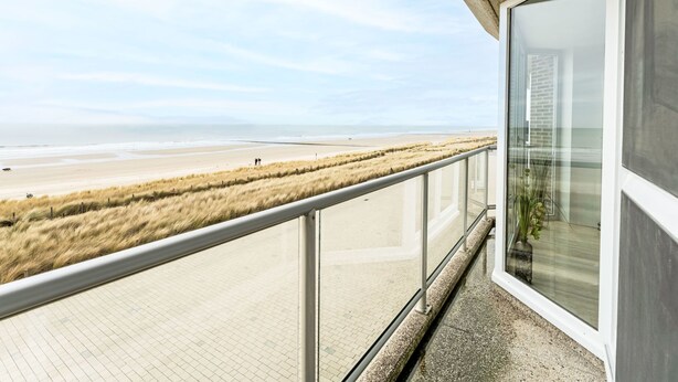 Ein Balkon mit Blick auf Strand und Dünen.