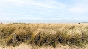 Ein Strand mit Dünen und einem Holzzaun.