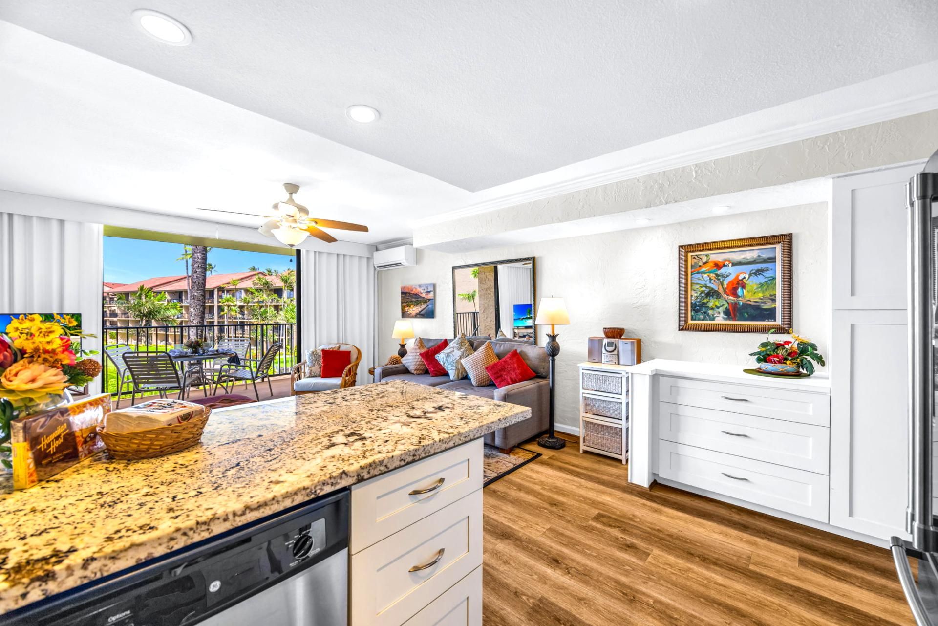 A modern kitchen with a granite countertop, white cabinetry, and a dining area with a view of the outdoors.