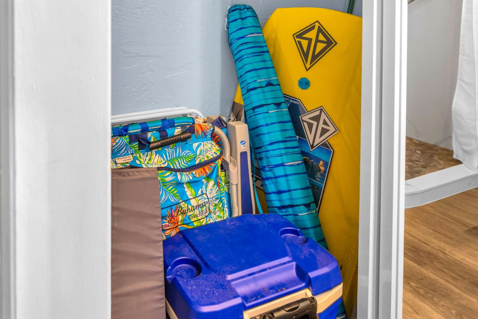 A storage area with various items including a blue container, colorful bags, and a yellow board with a geometric design.