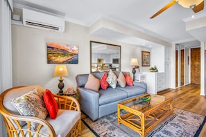 A living room with a sofa, armchairs, a coffee table, and a dining area with a lamp. - Papakea Villas | Ocean View Studio Sleeps 4 | Car Incl. w/ 6+ Nights | PKD-303 by KBM (Lahaina)