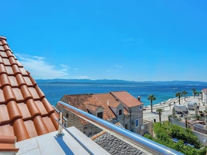Eine Küstenstadt mit terrakottafarbenen Dächern, blauem Himmel und Blick auf das Meer.