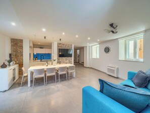 Eine moderne Küche mit Kochinsel, Essbereich mit Stühlen, einer Couch und einem großen Fenster.
