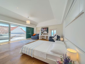 Ein modernes Schlafzimmer mit einem großen Bett, einem Fernseher und Meerblick.