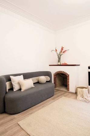 A living room with a grey sofa, a fireplace, a white wall, and a wooden floor. - Bathtub | WIFI | close to Polanco and Chapultepec (Ciudad de México)