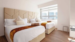 A modern hotel room with two beds, a large window, and a city view.