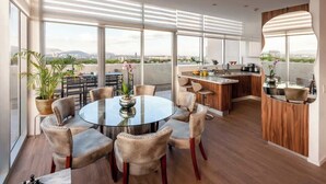 A modern kitchen with a dining area, large windows, and a view of the city.