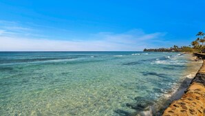 A beach with clear water, a stone walkway, and palm trees. - Papakea Villas | Ocean View 2 BR Sleeps 8 | Car Incl. w/ 6+ Nights | PKD ML-3523 by KBM (Lahaina)