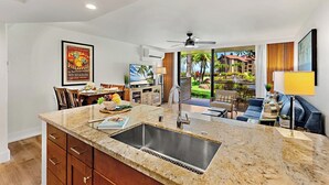 A modern kitchen with a granite countertop, stainless steel sink, and wooden cabinets. - Papakea Villas | Ocean View 2 BR Sleeps 8 | Car Incl. w/ 6+ Nights | PKD ML-3523 by KBM (Lahaina)