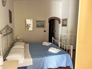 A bedroom with a bed, a nightstand, a mirror, and a door. - Villa Cecilia by Interhome (Capoliveri)