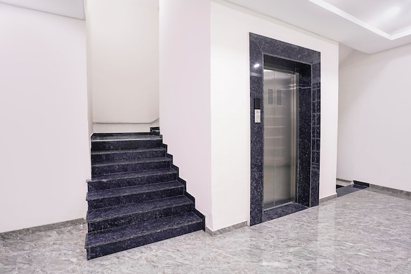 Una escalera que conduce a un ascensor en un edificio moderno con piso de mármol.
