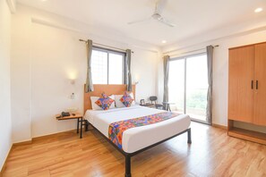 A hotel room with a bed, bedside table, nightstand, and a wardrobe. - Fabhotel Rova Stays (Pune)