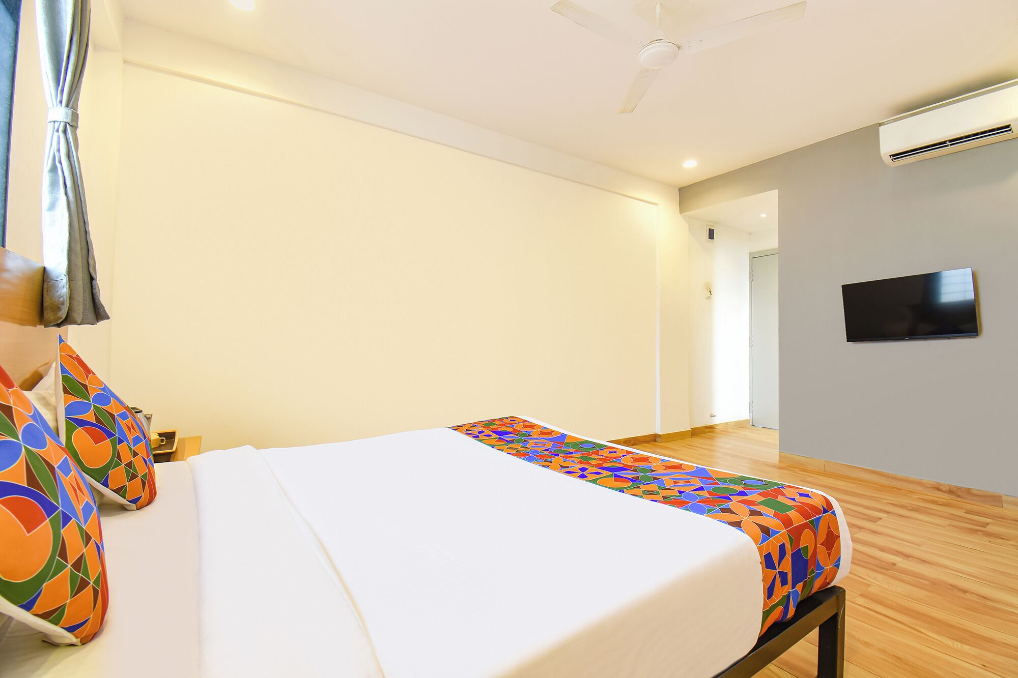 Une chambre d’hôtel avec un lit, un téléviseur fixé au mur et un appareil de climatisation.