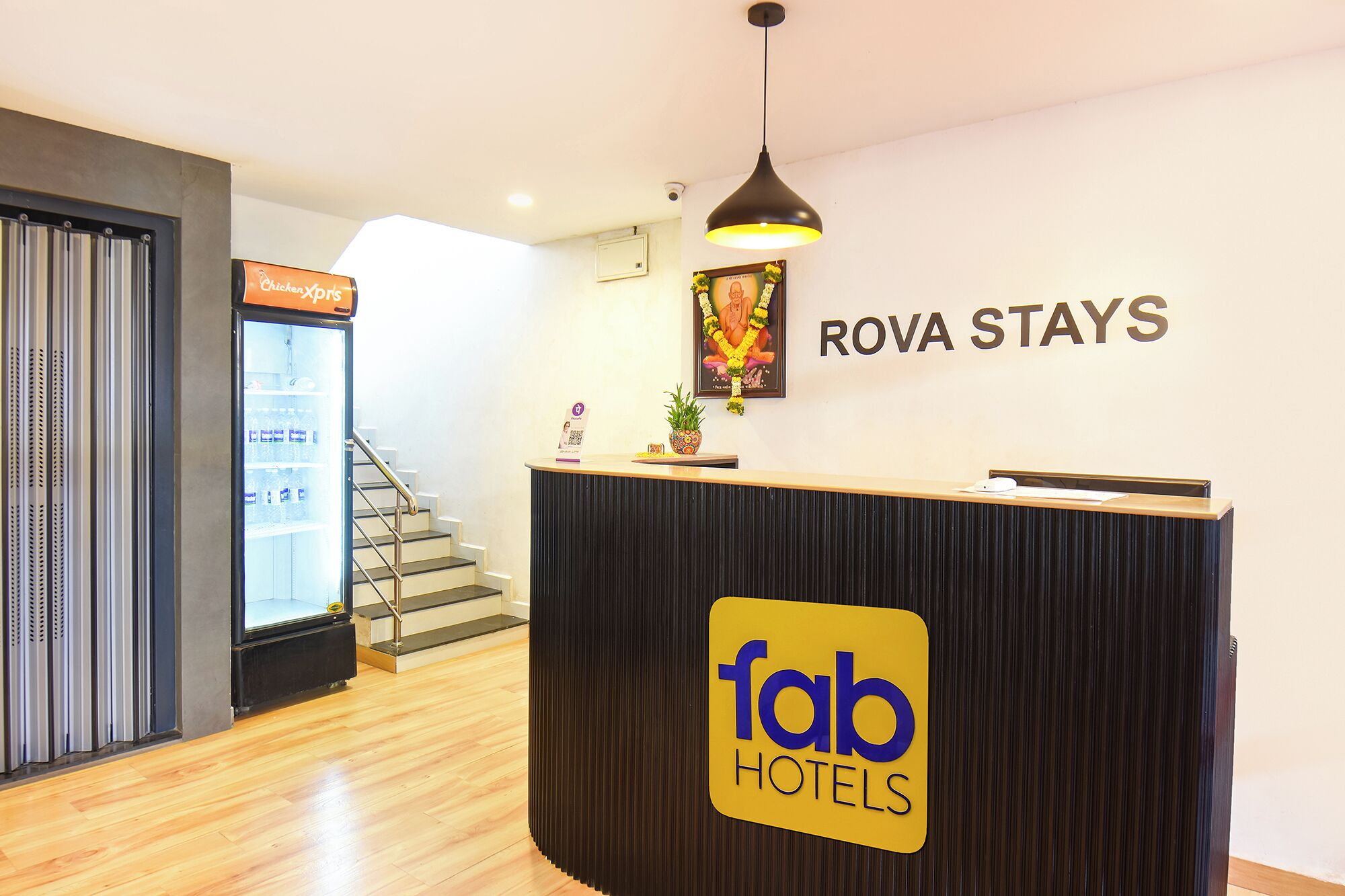 A reception desk with a sign for 'fab hotels' and a sign for 'Rova Stays' in the background.
