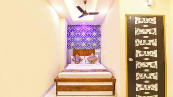 A bedroom with a bed, a ceiling fan, a patterned wall, and a door with a decorative design.