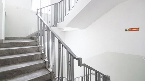 A staircase with metal railings leading to a landing. - Fabhotel Diamond Regency (Kolkata)