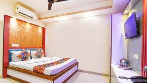 A bedroom with a bed, a ceiling fan, an air conditioner, a TV, and a desk with a phone. - Fabhotel Diamond Regency (Kolkata)