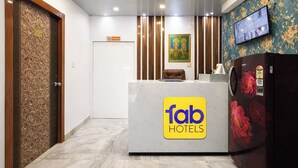 A reception desk with a 'fab hotels' sign, a wooden door with a number, and a TV on the wall. - Fabhotel Diamond Regency (Kolkata)