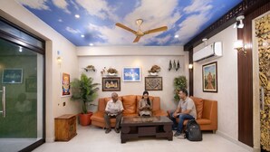 A room with a ceiling fan, a sofa, a coffee table, and potted plants.