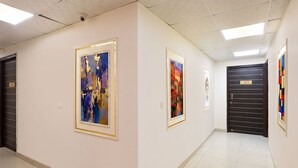 A hallway with framed artworks on the walls, a tiled floor, and a door with the number 403.