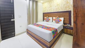 A hotel room with a bed, a nightstand, a telephone, and a door.