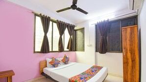 Une chambre à coucher avec un lit, un ventilateur de plafond et une fenêtre avec des rideaux.