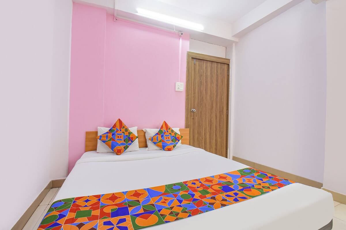 A bedroom with a bed, a wooden door, and a pink wall.
