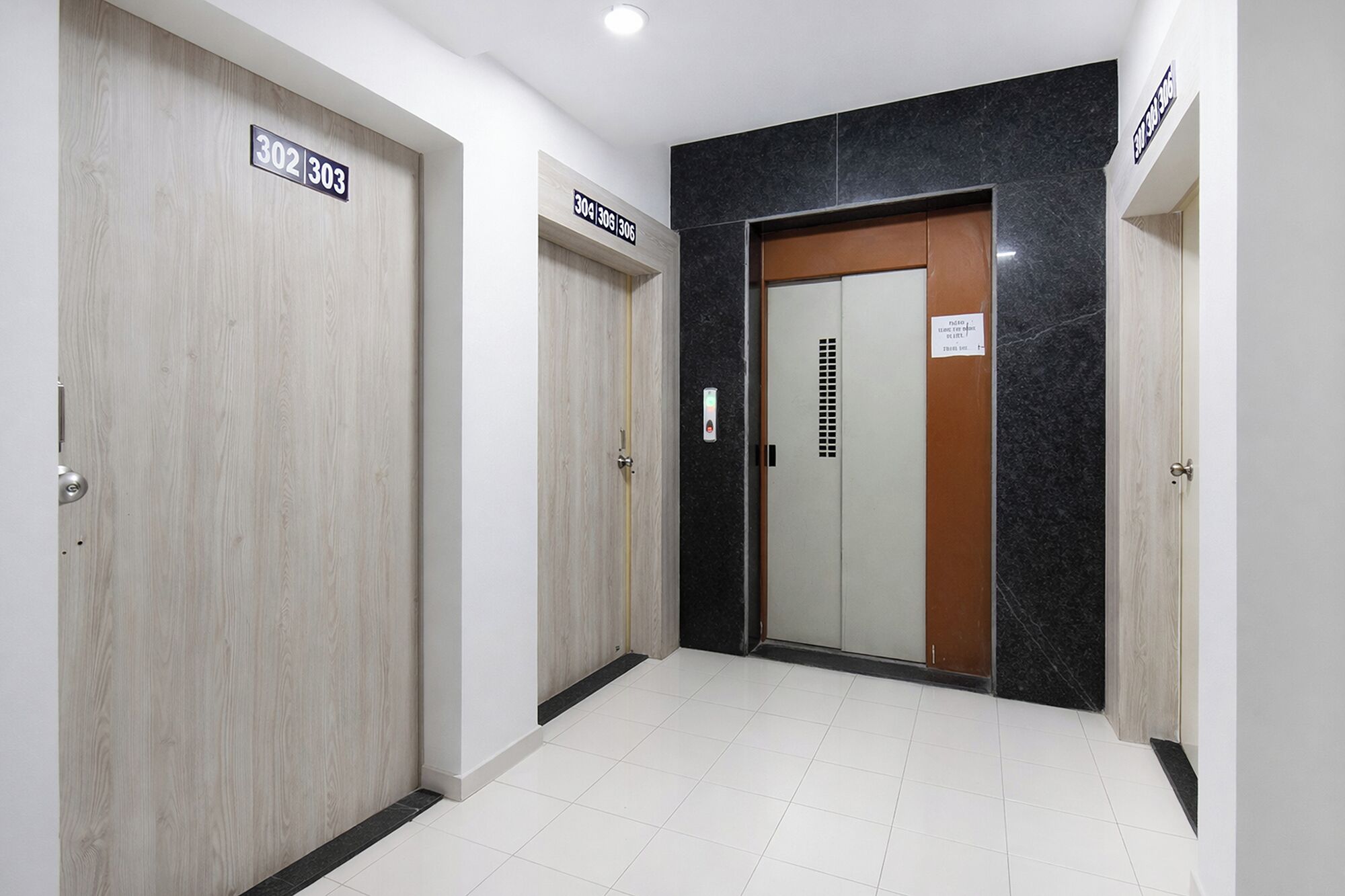 A hallway with doors labeled 302 and 303, a marble wall, and a tiled floor.